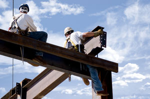 Two ironworkers atop the skeleton of a modern building, shot against a cloudy sky